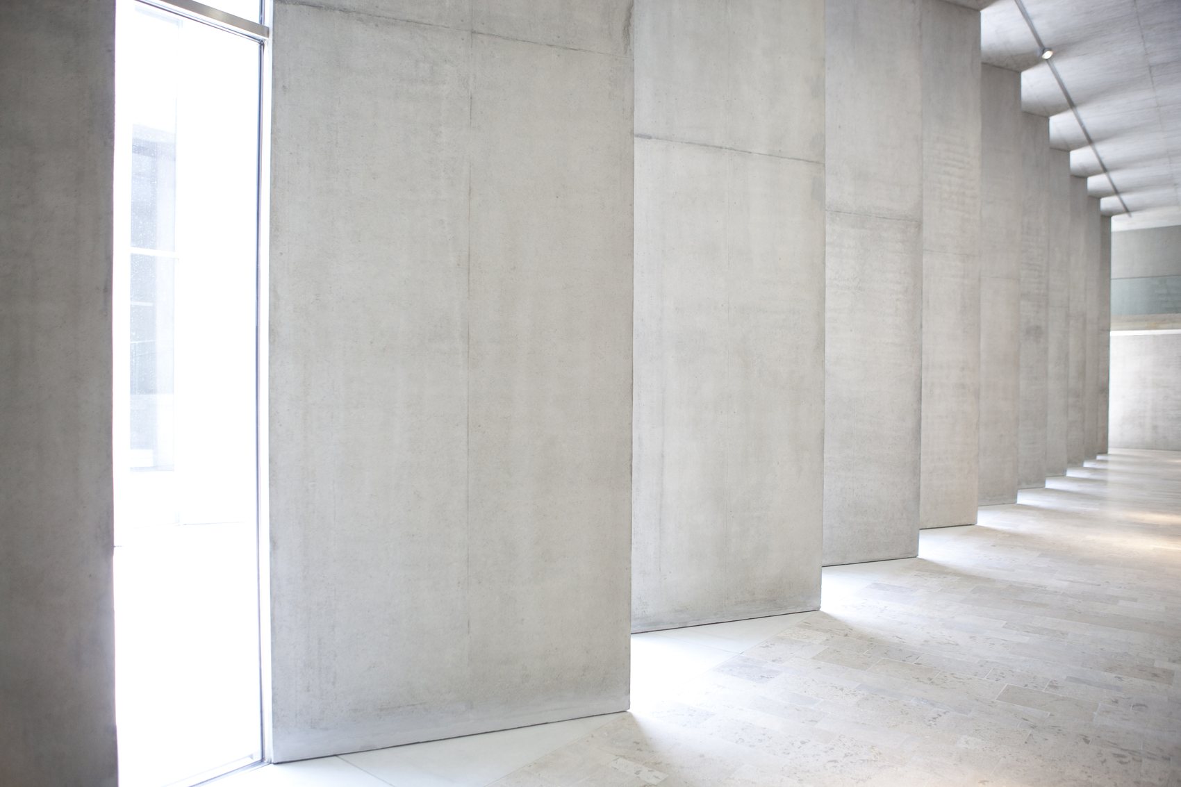 Daylight across a poured-concrete stair and column hall