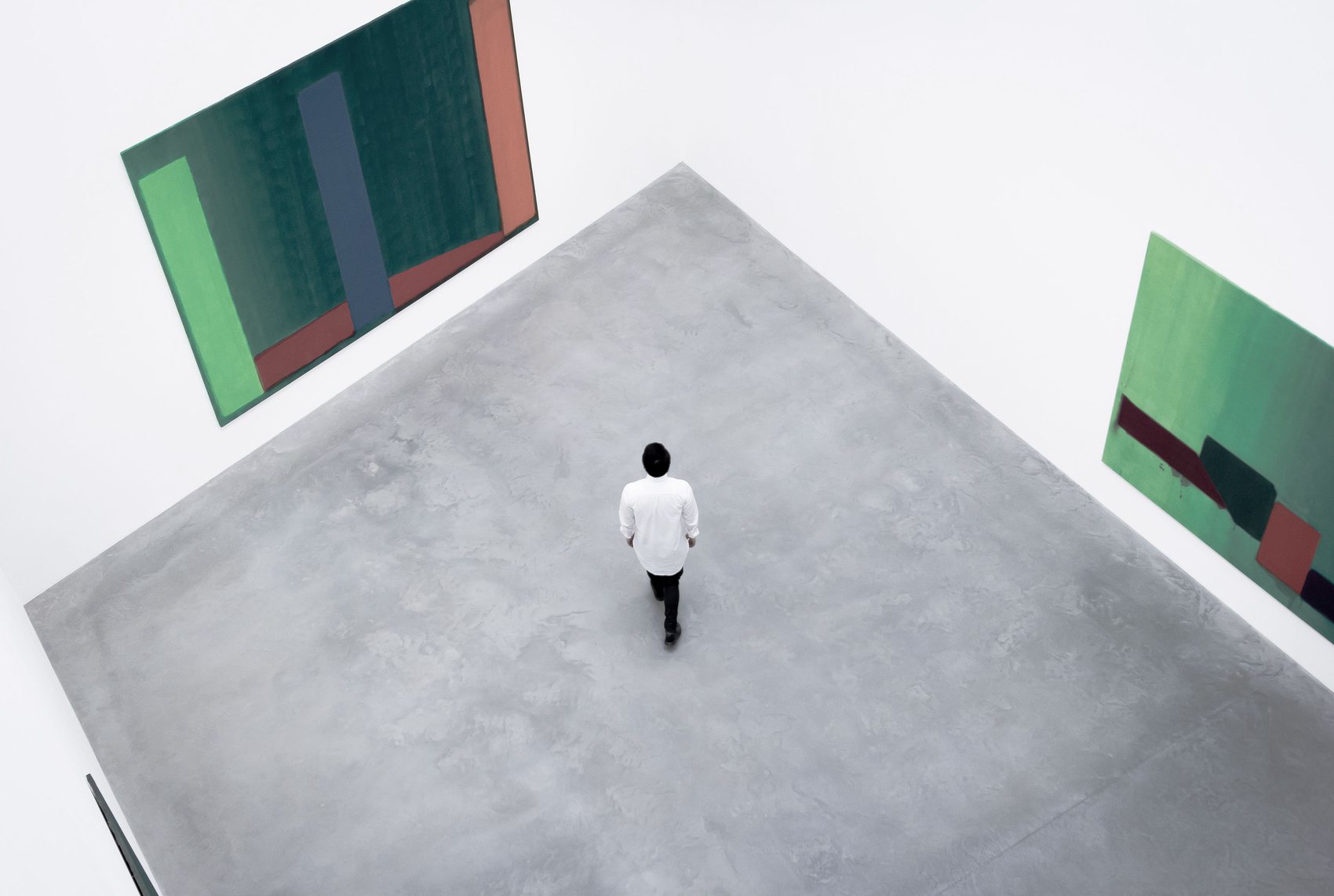 A figure alone in a large white gallery, seen from above
