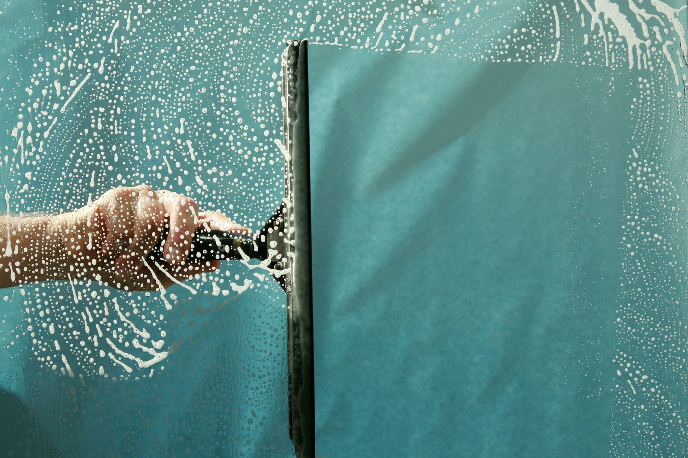 Gloved hands cleaning glass with professional product
